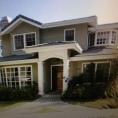 a house that is in the middle of some grass and plants on the front lawn