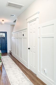 a living room with white walls and wood floors, blue door and green chair in the corner