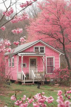 a small pink house surrounded by blooming trees