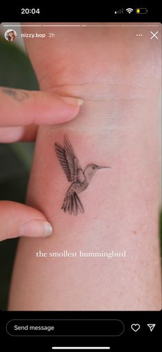 a small hummingbird tattoo on the back of a woman's left arm and wrist