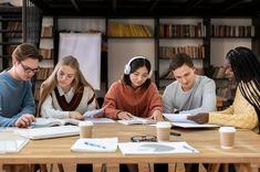 four people sitting at a table with books and papers