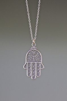 "A beautifully detailed Bali Silver Hamsa filigree charm simply dangles from a delicate silver chain. The chain measures 16\" with an extension to 18\" and is finished with a silver spring ring clasp. Please send a message if a different length chain is desired. The filigree detail in this charm is amazing! Hamsa Hand charm: 16x28mm Total length of pendant: almost 1 1/4\" Silver chain: 1mm All silver is sterling. As the owner, maker, designer, and curator of this shop, I take great pride in prov Sterling Silver Spiritual Necklace With Intricate Design, Spiritual Sterling Silver Necklace With Intricate Design, Delicate Silver Dangle Charm Necklaces, Sterling Silver Etched Necklaces For Wedding, Silver Filigree Symbolic Jewelry, Bohemian Sterling Silver Filigree Necklaces, Bohemian Sterling Silver Filigree Necklace, Silver Etched Dangle Jewelry, Ornate Engraved Dangle Jewelry