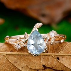 two gold rings with blue topazte and white diamonds on leafy brown leaves