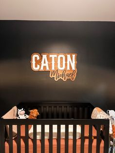 a baby crib in front of a black wall with the name caton michael on it