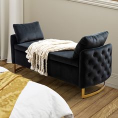 a black chair sitting on top of a hard wood floor next to a white bed