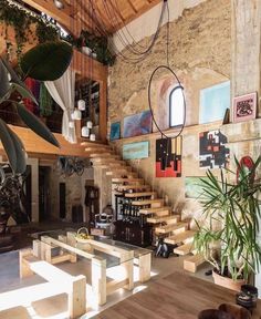 a living room filled with lots of furniture next to a wooden table and stair case