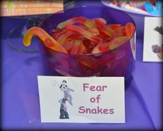 a bowl filled with gummy bears sitting on top of a table next to a sign that says fear of snakes