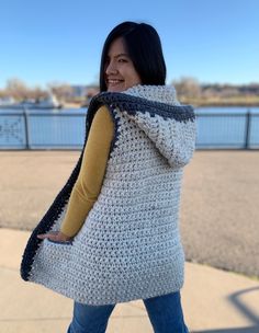 a woman wearing a white crocheted sweater and carrying a large gray tote bag