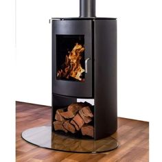 a black stove sitting on top of a wooden floor next to a pile of firewood