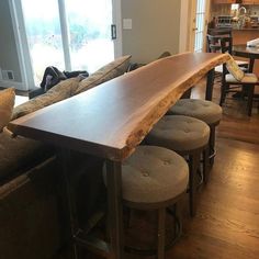 a wooden table sitting in the middle of a living room next to two stools