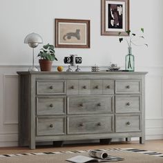 a dresser with drawers and pictures on the wall