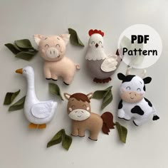 several felt farm animals are shown on a white surface