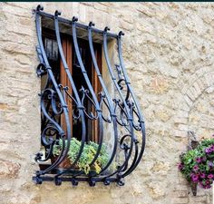 a window with iron bars and flower boxes on the side of an old stone building