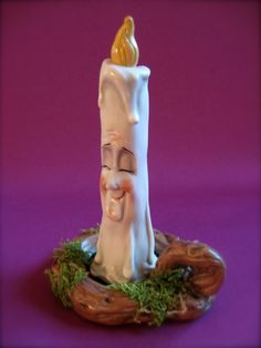 a small white candle with a smile on it's face sitting in a tree stump