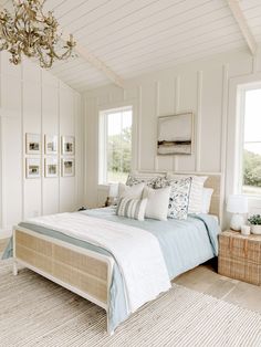 a bed sitting in a bedroom next to a window with a chandelier hanging from the ceiling