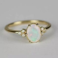 a white opal and diamond ring with three diamonds on the side, set in yellow gold