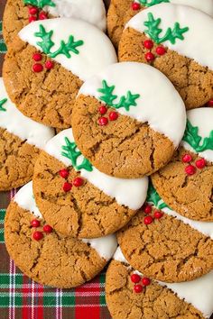 cookies decorated with white icing and holly decorations on a plaid table cloth, ready to be eaten