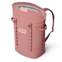 a pink yeti cooler bag with the lid open and straps down, sitting on a white surface