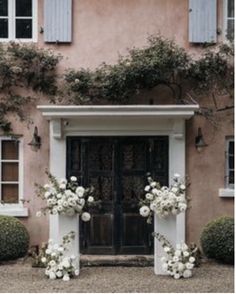 an entrance to a house with white flowers and greenery on the front door area