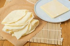 some food is sitting on top of a mat and next to a plate with cheese