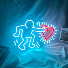 a neon sign with a man holding a heart on it's side, next to a book