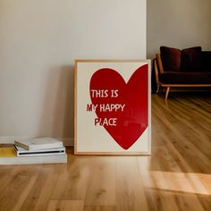 this is my happy place sign on the floor next to a stack of books and a couch