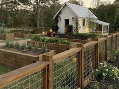 a fenced in garden area with various plants and vegetables growing on top of it