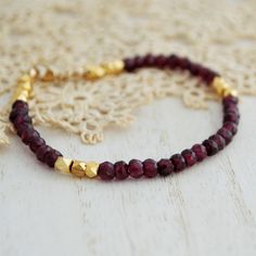 This dainty Garnet beaded bracelet features dark red faceted Garnet stones paired with 24kt gold plated copper beads. It is finished off with a gold-filled lobster clasp. The bracelet is also available in sterling silver with silver Pyrite beads instead of gold-plated ones. The beads measure 4 mm.  ----------------- FACTS ABOUT GARNET: ↦ Garnet inspires love, passion, and loyalty. ↦ It clears negativity. ↦ The birthstone for January. ↦ It is also the Wedding anniversary gemstone for the 2nd year Yellow Gold Faceted Beaded Bracelets, Gold Rondelle Beaded Bracelets With Gemstones, Gold Rondelle Gemstone Beaded Bracelets, Faceted Yellow Gold Beaded Bracelets, Bohemian Gold Rondelle Bracelets, Gold Bohemian Rondelle Bracelets, Festive Faceted Bead Bracelets, Festive Gold Hand-strung Bracelets, Elegant Festive Beaded Bracelets With Faceted Beads