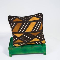 a decorative pillow sitting on top of a green stand with polka dots and lines painted on it