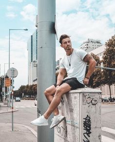 a man sitting on top of a pole next to a street