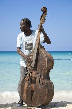 a man is standing on the beach with his instrument