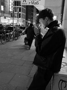 a man standing on the side of a street next to a building and eating something