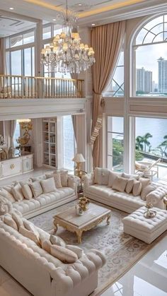 a living room filled with lots of white furniture and chandelier hanging from the ceiling