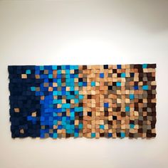 a piece of art made out of wood blocks on the wall with blue and brown squares