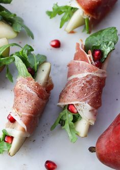 some food is laying out on a white surface with pomegranate and pears