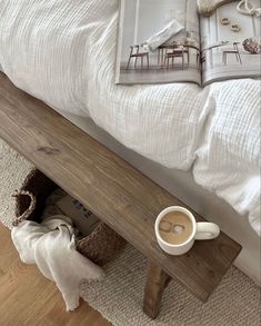 a coffee cup sitting on top of a wooden bench next to a book and magazine