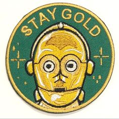 a green and yellow patch with the words stay gold on it's face, in front of a white background