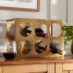 a gold wine rack with six bottles and two glasses