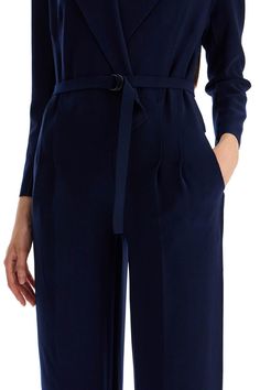 Made of comfortable poly lycra with laser-cut trims, this Norma Kamali jumpsuit boasts a surplice top that replicates a double-breasted jacket with peaked lapels, padded shoulders and an internal hook-and-loop closure. The waist is defined by front pleats and a matching D-ring belt, then falls into a pair of fluid, straight pants with side pockets. The model is 177 cm tall and wears a size XS. Composition: 95%PL, 5%EA Sleek V-neck Jumpsuits And Rompers For Work, Formal Solid Belted Jumpsuit, Elegant Jumpsuits With Belted Cuffs, Chic Workwear Jumpsuits And Rompers With Belted Cuffs, Chic Jumpsuits And Rompers With Belted Cuffs For Work, Sleek V-neck Jumpsuit For Workwear, Sleek Fall Workwear Jumpsuits And Rompers, Sleek Workwear Jumpsuits And Rompers For Fall, Belted Long Sleeve Jumpsuits For Work