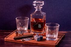 a bottle of alcohol and two shot glasses on a wooden tray next to a corkscrew