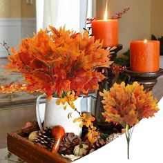 an arrangement of autumn leaves and candles on a table