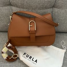 Nwt Furla Flow Top Handle M Bag (Medium Size Of The Range). It Can Be Carried By Hand, Worn On The Shoulder Or Crossbody. Purchased Directly From Furla And A New Edition, But I’m Cleaning Out My Bag Collection. Interior Details 1 Flat Open Pocket Exterior Details Fula Logo/Single Handle/Open Pocket On The Back Material Claris Lux Calf Leather Strap Information Removable/Adjustable Leather Strap Strap Length Max 42.52 In Strap Length Min 37.6 In Closure Magnet Closure Hardware Furla Arch Gasket Product Code Wb00996_bx2045_1007_ry000 Plating Gold Dimensions In Inch 9,84 X 6,1 X 3,15 (W X H X D) - Open Inside Pocket - Open Outside Pocket On The Back - Short Leather Top Handle - Adjustable Daily Use Flap Bag With Branded Hardware, Elegant Saddle Bag With Adjustable Strap For Shopping, Elegant Flap Satchel, Elegant Saddle Bag With Removable Pouch For Shopping, Flap Shoulder Bag With Branded Hardware For Shopping, Elegant Saddle Bag With Branded Hardware For Daily Use, Elegant Crossbody Saddle Bag For Shopping, Shopping Flap Satchel With Detachable Strap, Shopping Satchel With Detachable Strap And Flap