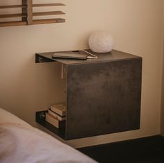 a book shelf with a phone on top of it next to a bed in a bedroom