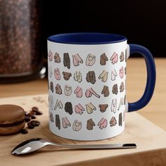 a blue and white coffee mug sitting on top of a wooden table next to a cookie