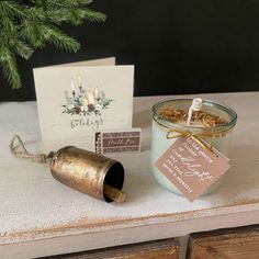 a candle and some cards are sitting on a table next to a christmas ornament