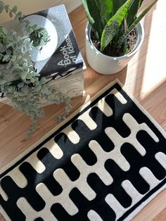 a black and white rug sitting on top of a wooden table next to a potted plant