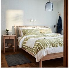 a bed with green and white comforter in a bedroom next to a wooden table