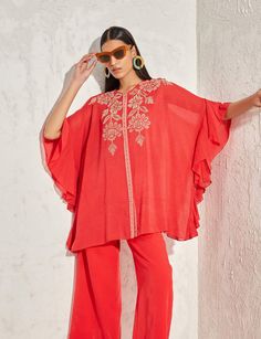 Editor's Note A red forsythia kaftan top features beautiful floral embellishments. It is a loose, flowy top that drapes over the body and is made from a lightweight fabric, perfect for warm weather. Note: Pants worn by model is for styling purposes only Color: Red Fabric: Georgette Component: Kaftan and inner Occasion: Daywear and resort Embroidery: Floral hand & machine embellishment Disclaimer: Product color may slightly vary due to photographic lighting sources or your monitor setting. Care: Bohemian Spring Short Sleeve Sets, Bohemian Short Sleeve Sets For Spring, Spring Bohemian Short Sleeve Sets, Summer Vacation Tunic Sets, Traditional Summer Sets With Cape Sleeves, Summer Festive V-neck Kaftan, Festive Summer Dress With Cape Sleeves, Bollywood Embellished Summer Sets, Bollywood Embellished Sets For Summer