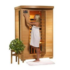 a woman in a white towel is standing next to a sauna