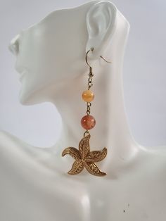 "These were made from two vintage starfish pendants that I lucked out and found on two separate occasions. I used a combo of golden and burnt orange Carnelian beads because when I envision a starfish, the variation with this color.... Asterias Rubens, which is the most common, is the first that pops in my mind.  Feel free to reach out with any questions. Thanks for looking and have a blessed day! Did you know that a starfish can regenerate its limbs at any given time? Or that they can digest prey outside of their bodies, so they are able eat prey much larger than their mouths? Let these little starfish or \"sea stars\" be a reminder to you that after defeat comes growth and even if you bit off more than you can chew, you can still make a feast out of it!" Bohemian Gold Starfish Jewelry, Bohemian Star-shaped Gold Jewelry, Vintage Adjustable Star Jewelry, Vintage Adjustable Star-shaped Jewelry, Adjustable Vintage Star-shaped Jewelry, Bohemian Gold Star Jewelry, Bohemian Gold Carnelian Jewelry, Bohemian Gold Starfish Charm Jewelry, Vintage Beach Dangle Earrings